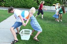 two children playing with a laundry basket on the grass