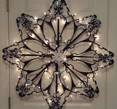 a metal snowflake with lights hanging from it's sides in front of a door