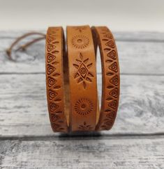 two brown leather bracelets sitting on top of a wooden table