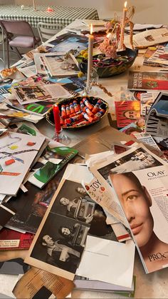 the table is covered with magazines and candles