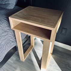 a wooden table sitting on top of a bed next to a night stand and nightstand