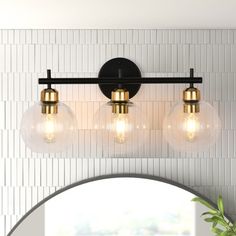 three light bathroom vanity fixture with glass globes and black metal frame, in front of a white tiled wall