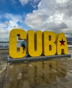 a large yellow sign that says cuba with a person standing next to it in front of the letters