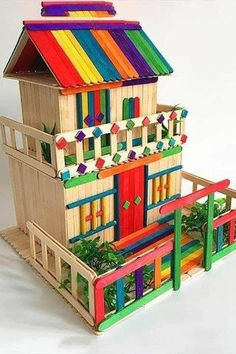 a toy house made out of wood with colorful doors and windows on the top floor