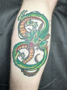 a green and yellow dragon tattoo on the left arm, with an orange snake coming out of it's mouth