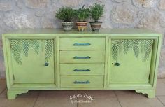 two potted plants sit on top of a green dresser