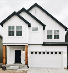 a large white house with two garages on the front and one door is open