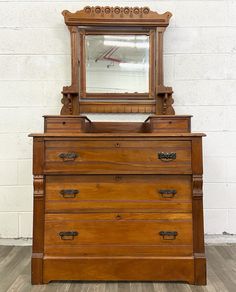 an old wooden dresser with a mirror on it's top and drawers below the drawer