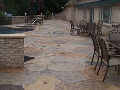 an outdoor patio with tables and chairs next to a pool