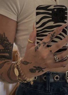 a person with tattoos holding a cell phone