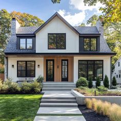 a white house with black windows and steps leading up to the front door