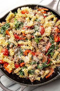 a skillet filled with pasta and vegetables