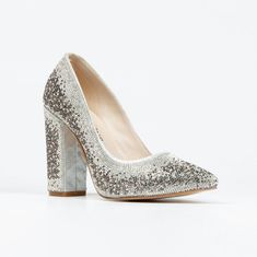 a pair of silver glitter high heels on a white surface, with the heel up