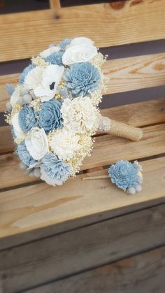 a bridal bouquet sitting on top of a wooden bench with blue and white flowers