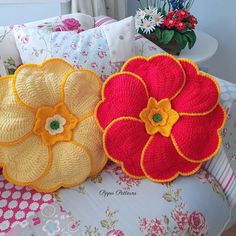 two crocheted flower pillows sitting on top of a couch next to each other