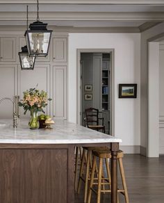 a kitchen island with two stools in front of it and a light fixture hanging from the ceiling