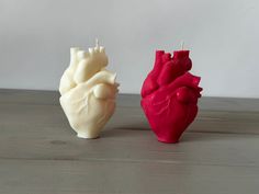 two heart shaped candles sitting on top of a wooden table