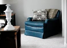 a blue chair sitting in a living room next to a lamp and a white door