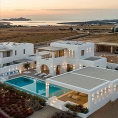 an aerial view of a large white house with swimming pool and patio area at dusk