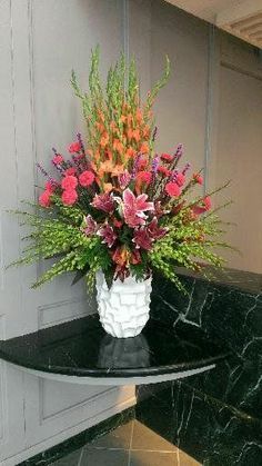 a vase filled with flowers sitting on top of a black table next to a wall