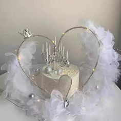 a heart shaped cake decorated with white feathers and silver decorations on top of a table