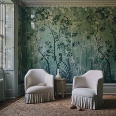 two white chairs sitting in front of a green wall