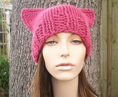 a female mannequin head wearing a pink knitted hat with cat ears on it