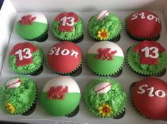 twelve decorated cupcakes in a white box with green and red frosting on them