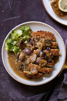 a white plate topped with meat covered in mushroom gravy next to a salad