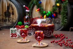 two red wine glasses sitting on top of a table next to some barrels with christmas decorations