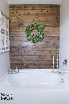 a white bath tub sitting next to a wooden wall with a wreath on the wall