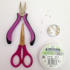 two pairs of pink scissors next to a spool of thread and beading supplies