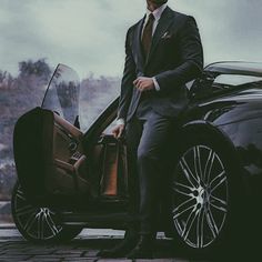 a man in a suit standing next to a car