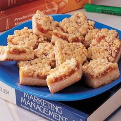 a blue plate topped with pieces of cake next to books on a white counter top