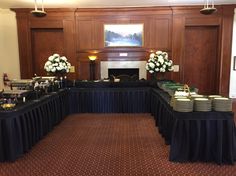 a banquet room with tables covered in black tablecloths and white flowers on top of them