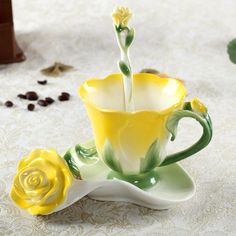 a yellow and white coffee cup sitting on top of a saucer with a flower in it