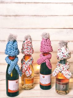 four crocheted hats and two bottles of wine on a white wooden surface with lights behind them