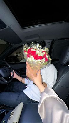 a woman sitting in the driver's seat of a car with flowers on her head