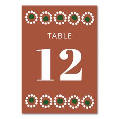 an orange table number card with white numbers and green dots on the border, in red