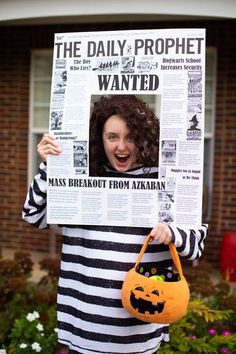 a woman in striped shirt holding up a newspaper with a pumpkin bag on her chest