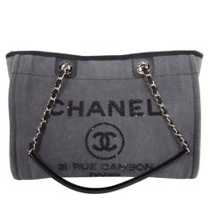 Authentic LIKE NEW Chanel Deauville blackish grey shoulder bag tote. Features blackish grey lightly washed denim canvas with the inscriptions "CHANEL, 21 RUE CAMBON PARIS" embroidered in brilliant black sequins, black interior, zipper pocket and two slip pockets, and silver hardware, magnetic snap closure. The hologram stamp and the card read: 23841550 Made in Italy 2017 Strap drop: 10.5" Grey Shoulder Bag, Leather Formal Shoes, White Mark, Bag Packaging, Washed Denim, Shopping Tote, Black Sequins, Tote Bag Design, Canvas Leather