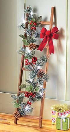 a wooden ladder decorated with christmas decorations and bows, next to a small gift box