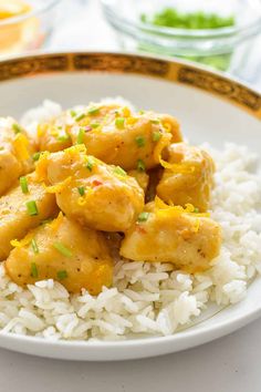 a white plate topped with rice and chicken covered in sauce on top of green onions