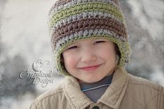 a young boy wearing a crocheted hat and smiling