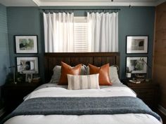 a bed with two pillows and some pictures on the wall next to it in front of a window