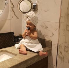 a baby sitting on top of a bathroom counter