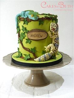 a green cake decorated with an animal and name on the top is sitting on a plate