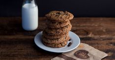 a stack of cookies sitting on top of a white plate next to a bottle of milk