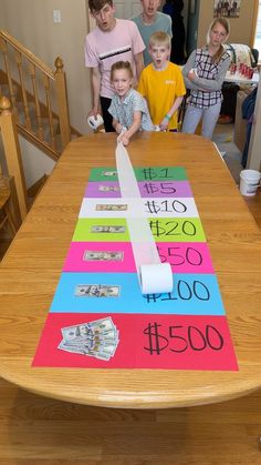 a group of kids standing around a table with some money on it and one kid holding a roll of toilet paper