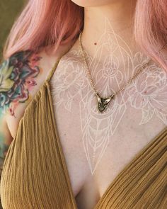 a woman with pink hair and tattoos on her chest is wearing a gold halter top